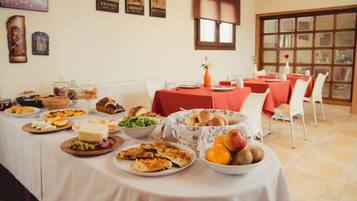 A dining area with tables set for a meal, featuring various dishes and a basket of bread.