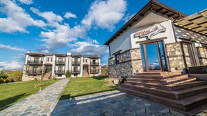 A two-story building with a stone facade, a wooden balcony, and a clear sky. - Paroraia boutique rooms (Sintiki)
