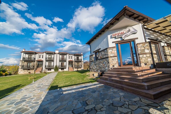 A two-story building with a stone facade, a wooden balcony, and a clear sky. - Paroraia boutique rooms (Sintiki)