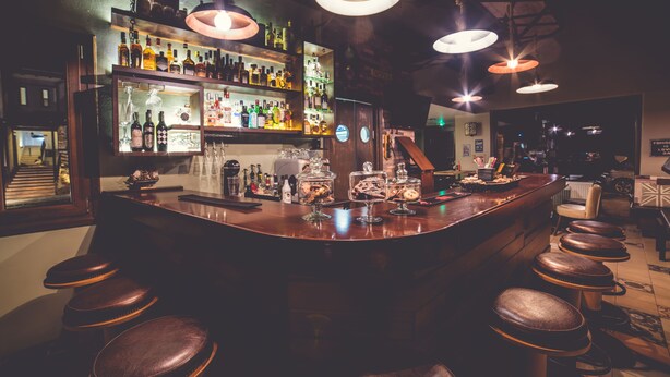 A bar area with stools, shelves of bottles, and hanging lights. - Paroraia boutique rooms (Sintiki)
