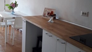 A kitchen with white cabinets, a wooden countertop, and a dining area with a table and chairs. - il balcone sul lago (Magreglio)