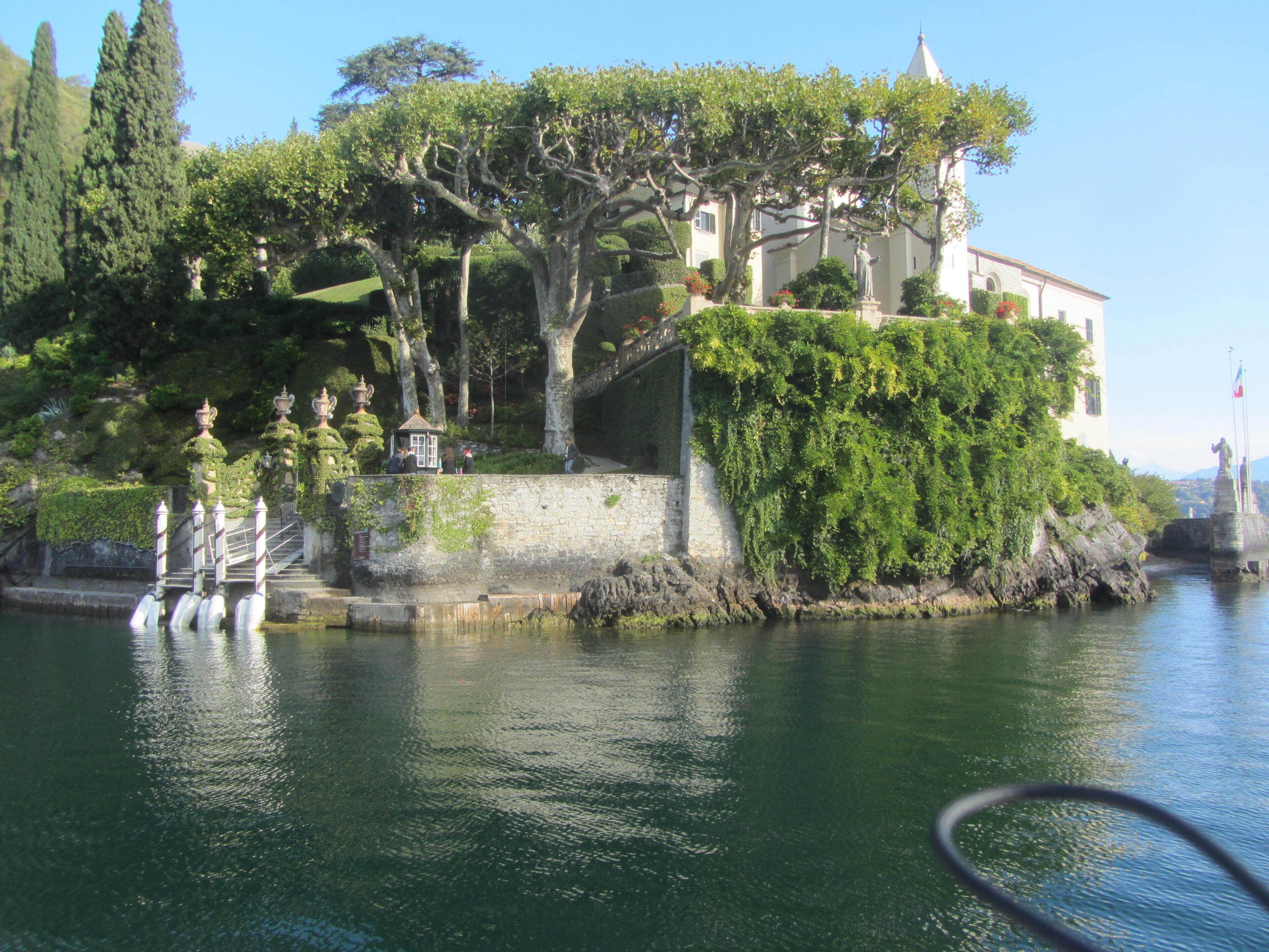 A historic building with a stone staircase leading up to a terrace, overlooking a body of water.