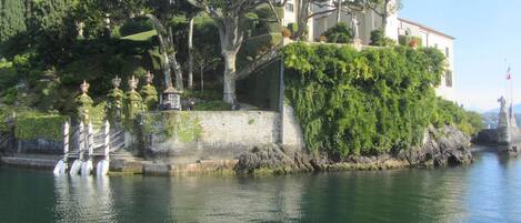 A historic building with a stone staircase leading up to a terrace, overlooking a body of water.