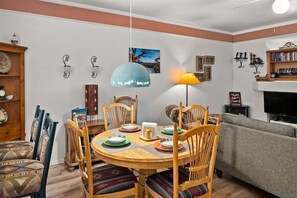 A dining area with a round wooden table, chairs, and a lamp.