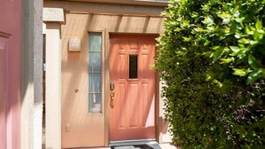 La entrada de una casa con puerta de madera, una ventana pequeña y un buzón.
