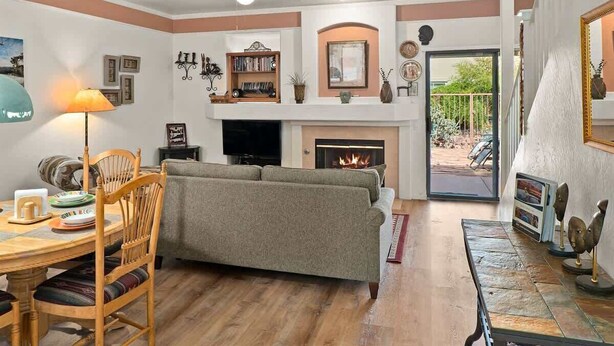 Una sala de estar acogedora con chimenea, un sofá, una mesa de comedor con sillas y un ventilador de techo.