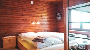 Ein holzverkleideter Raum im Blockhausstil mit einem Bett, einem Nachttisch und einem Fenster.