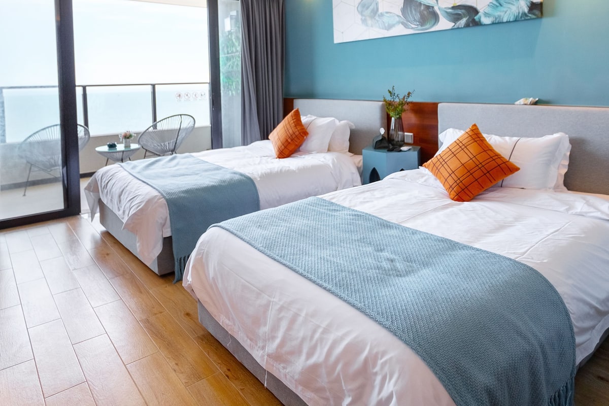 Ett hotellrum med två sängar, en balkong och ett stort fönster.