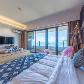 A modern hotel room with a large bed, a flat-screen TV, a small table, and a view of the sea through large windows. - Yi Shu Jing Pin Holiday Hotel (Shanwei)