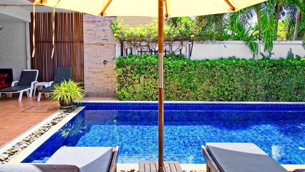 Una piscina con sillas de descanso y una pérgola.