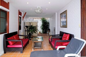 Ein modernes Interieur mit einer Sitzecke, einem Ventilator und Blick in einen anderen Raum.