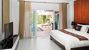 Un dormitorio con una cama grande, televisor y puerta corrediza de vidrio que da a un espacio exterior con piscina y sillas de descanso.