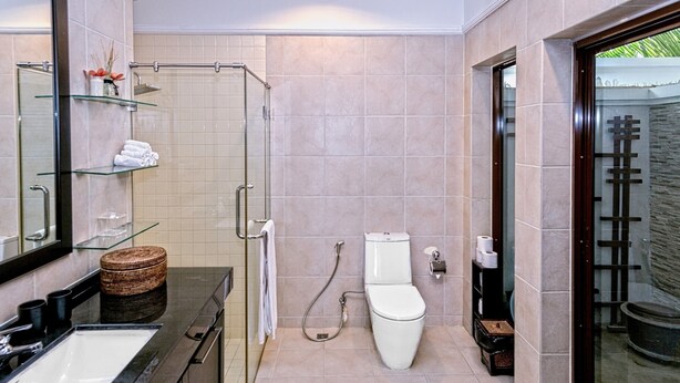 A modern bathroom with a glass shower enclosure, a white toilet, and a vanity with a sink and mirror. - Busaba Villa 7 - 3 Bedroom - Pool (Tambon Nong Kae)