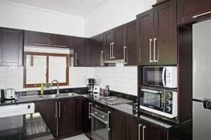 Une cuisine moderne avec des meubles de couleur sombre, un évier en acier inoxydable, un lave-vaisselle Bosch, une machine à café, un grille-pain, un four à micro-ondes et un four encastré.