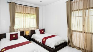 A hotel room with two beds, beige curtains, white bedding, and a wooden headboard. - Busaba Villa 7 - 3 Bedroom - Pool (Tambon Nong Kae)