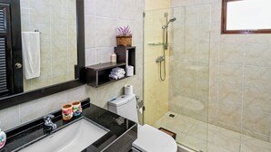 A bathroom with a sink, toilet, and glass-enclosed shower. There are shelves with toiletries and a mirror above the sink. - Busaba Villa 7 - 3 Bedroom - Pool (Tambon Nong Kae)