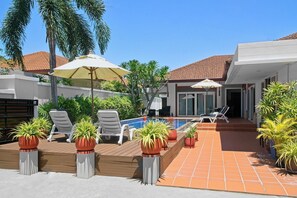 Un espace piscine aménagé avec des chaises longues et des plantes en pot.