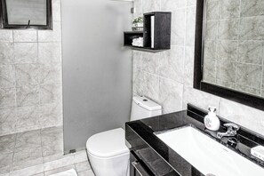 Een moderne badkamer met toilet, wastafel en douche.