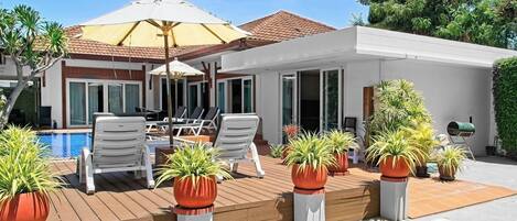 Uma casa moderna com piscina, área de estar externa e plantas em vasos.