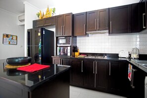 Een moderne keuken met donkere kastjes, een zwarte koelkast, een magnetron en een broodrooster.