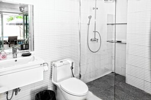 Een moderne badkamer met een wit wastafel, toilet en douchecabine met glazen wanden.