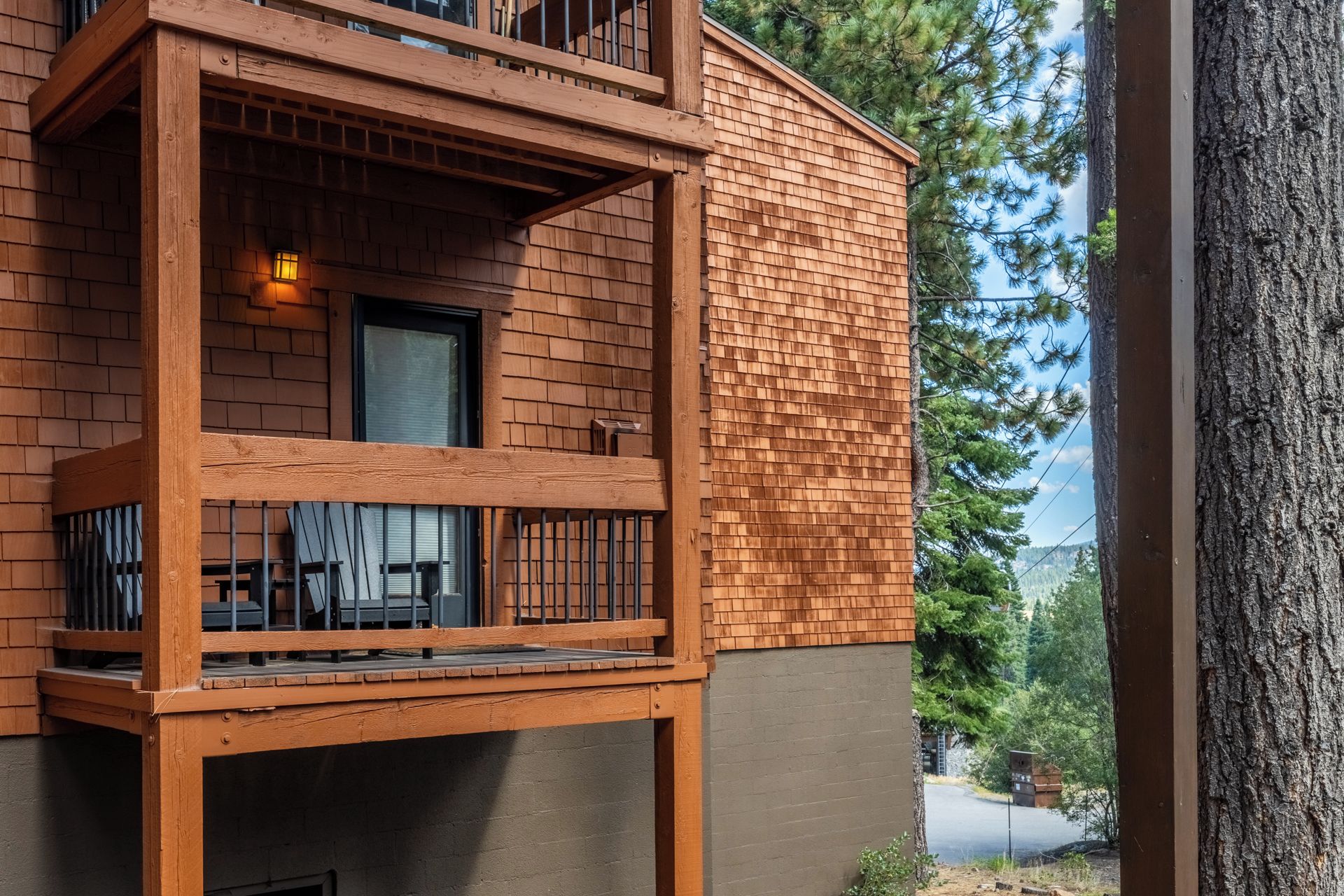 A two-story building with a balcony, a window, and a view of trees and a road.