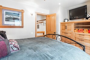 Un dormitorio con una cama, un armario de madera, un televisor y una fotografía enmarcada en la pared.