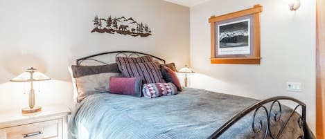 A bedroom with a bed, bedside tables, a wall-mounted picture, and a ceiling fan.