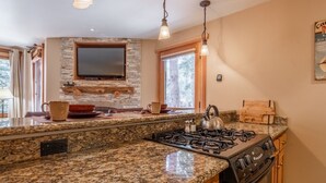 Una cocina con encimeras de granito, estufa a gas, horno empotrado y salpicadero de pared de piedra.