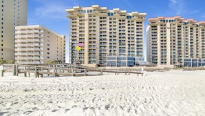 A beachfront hotel with multiple high-rise buildings, a sandy beach, and a wooden boardwalk. - Beachfront 1BR @ Phoenix I • Sleeps 6 • Stunning Views, Pool, Splash Pad & Beach Access (Orange Beach)