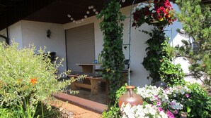 A garden with a wooden bench, a hanging flower pot, and a tiled pathway.