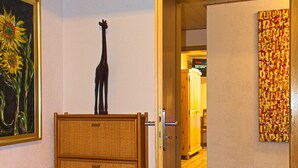 Una habitación con un aparador de mimbre, un cuadro de girasoles y una escultura de jirafa.