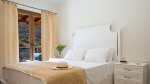 A bedroom with a bed, a nightstand, a dresser, and a window with curtains.