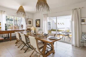A dining area with a wooden table and chairs, a hanging light fixture, and a view of the outdoors. - Casa Grande (Javea / Xàbia)