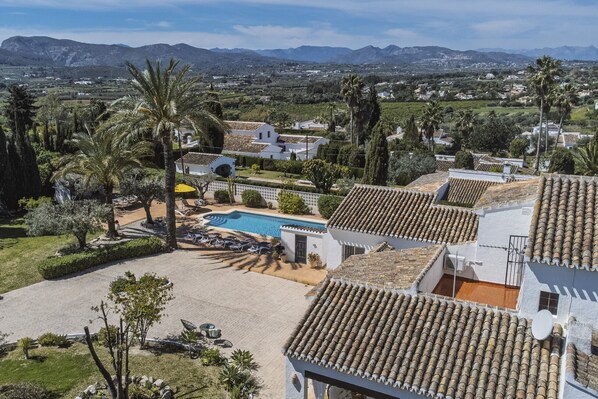 A residential area with a swimming pool, palm trees, and a mountainous backdrop. - Casa Grande (Javea / Xàbia)