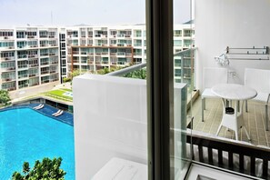 Ein modernes Hotelzimmer mit Balkon, das einen Blick auf einen Swimmingpool und angrenzende Gebäude bietet.