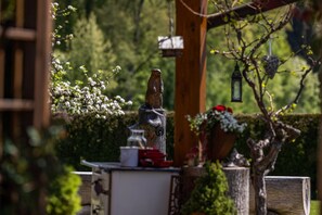 A garden with a wooden sculpture, a birdhouse, and a lantern. - Ferienwohnung Kehlstein, 2 Personen, 58 qm (Schönau am Königssee)