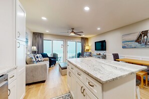 Relax in a spacious living area with a sofa and dining table, enjoy a kitchen with white cabinetry, and take in the view from the large window.