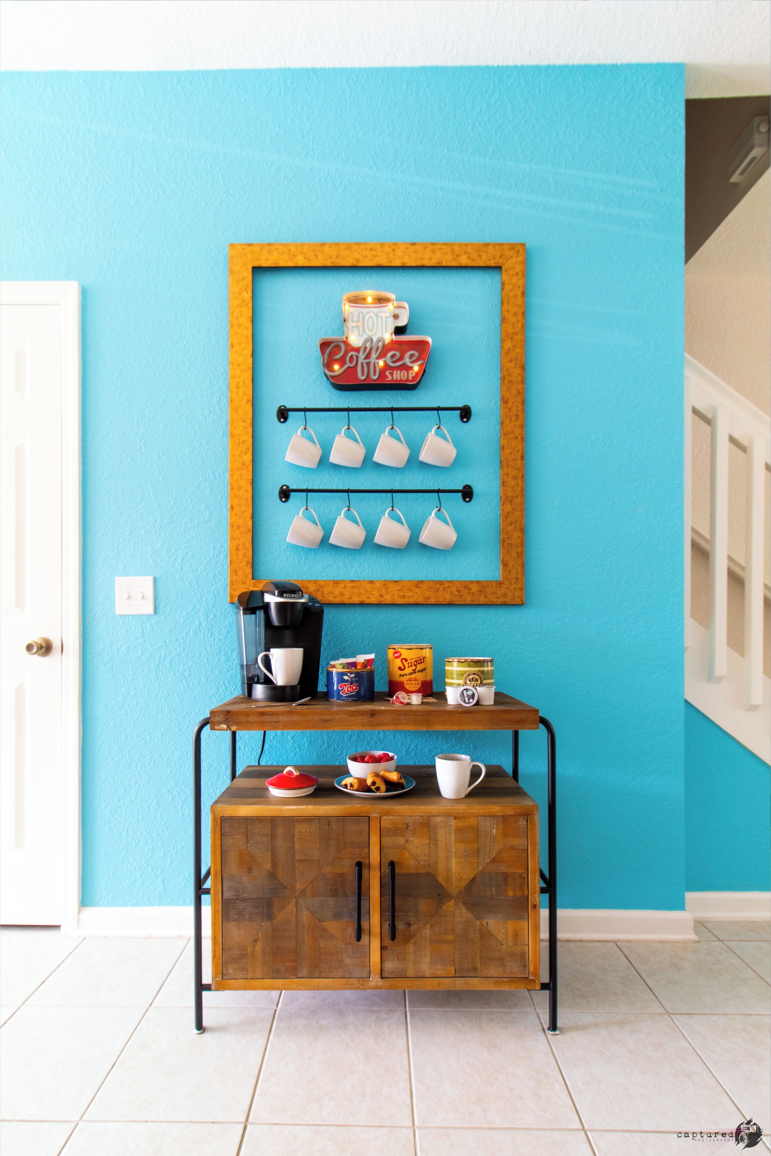 A kitchen area with a coffee station, including a coffee maker, cups, and a sign that reads "Hot Coffee Shop."