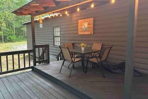 A wooden cabin with a covered porch, a dining table with chairs, and a small window. - "Cottage @ JP Coleman"-perfect getaway at Pickwick (Iuka)
