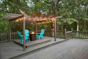 A wooden deck with a pergola, two turquoise chairs, and a central table with a fire feature. - "Cottage @ JP Coleman"-perfect getaway at Pickwick (Iuka)
