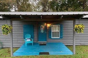 A small, single-story house with a blue front door, a window, and a porch with a blue mat. - "Cottage @ JP Coleman"-perfect getaway at Pickwick (Iuka)