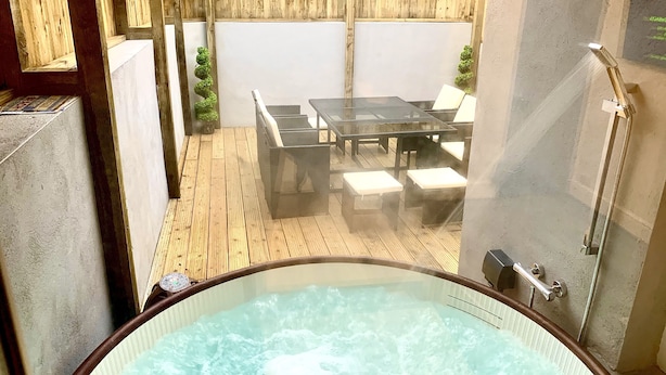 Un área de hidromasaje con terraza de madera, asientos exteriores y ducha.