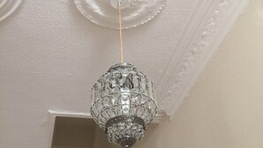 Un lampadario con decorazioni in cristallo appeso a un soffitto con modanature decorative.