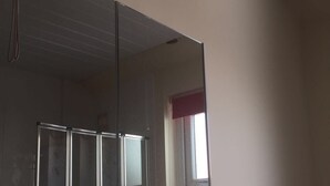 Una stanza con un grande specchio, una finestra con una tenda rossa e un soffitto bianco.