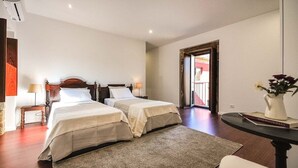 Habitación de hotel con dos camas, una mesita, una silla y vistas al exterior.