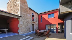 Un patio con una mesa y sillas, un edificio de piedra y un edificio rojo con balcón.