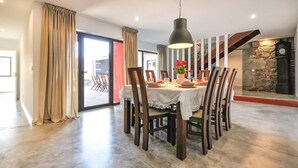 Un comedor con una mesa redonda, sillas de madera y una lámpara colgante.