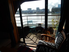 Ein Zimmer mit Flussblick, ein Balkon mit Tisch und Stühlen sowie ein Stuhl mit ZEBRA-Muster.