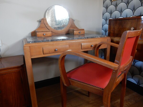 Ein Schreibtisch aus Holz mit Spiegel, Schubladen und einem roten Sitzmöbel.